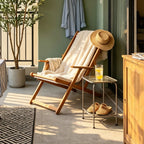 Olive tree on a shaded porch next to a wooden sling chair, straw hat and cold drink