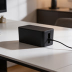 Black cable case on a desk near a window with a cord running out to the outlet