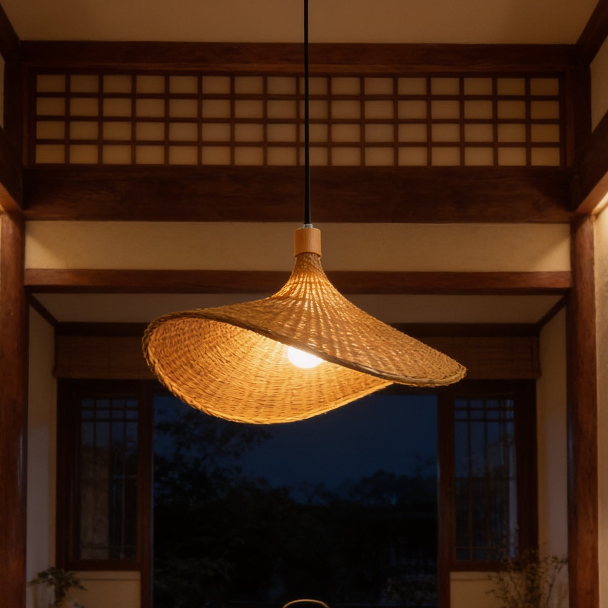 Woven straw hat pendant lit close up in front of a wooden lattice screen at dusk