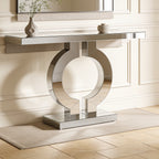 Silver ring base console viewed head on above pale stone flooring