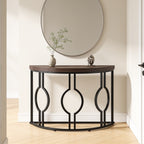 Black framed half moon console under a round mirror in a narrow hallway