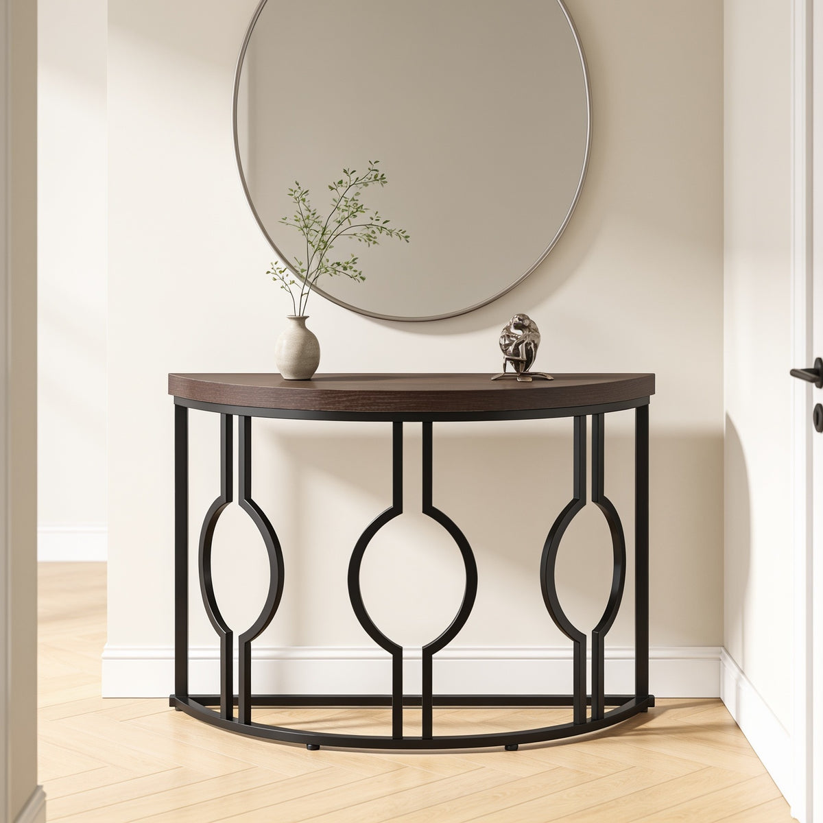 Black framed half moon console under a round mirror in a narrow hallway
