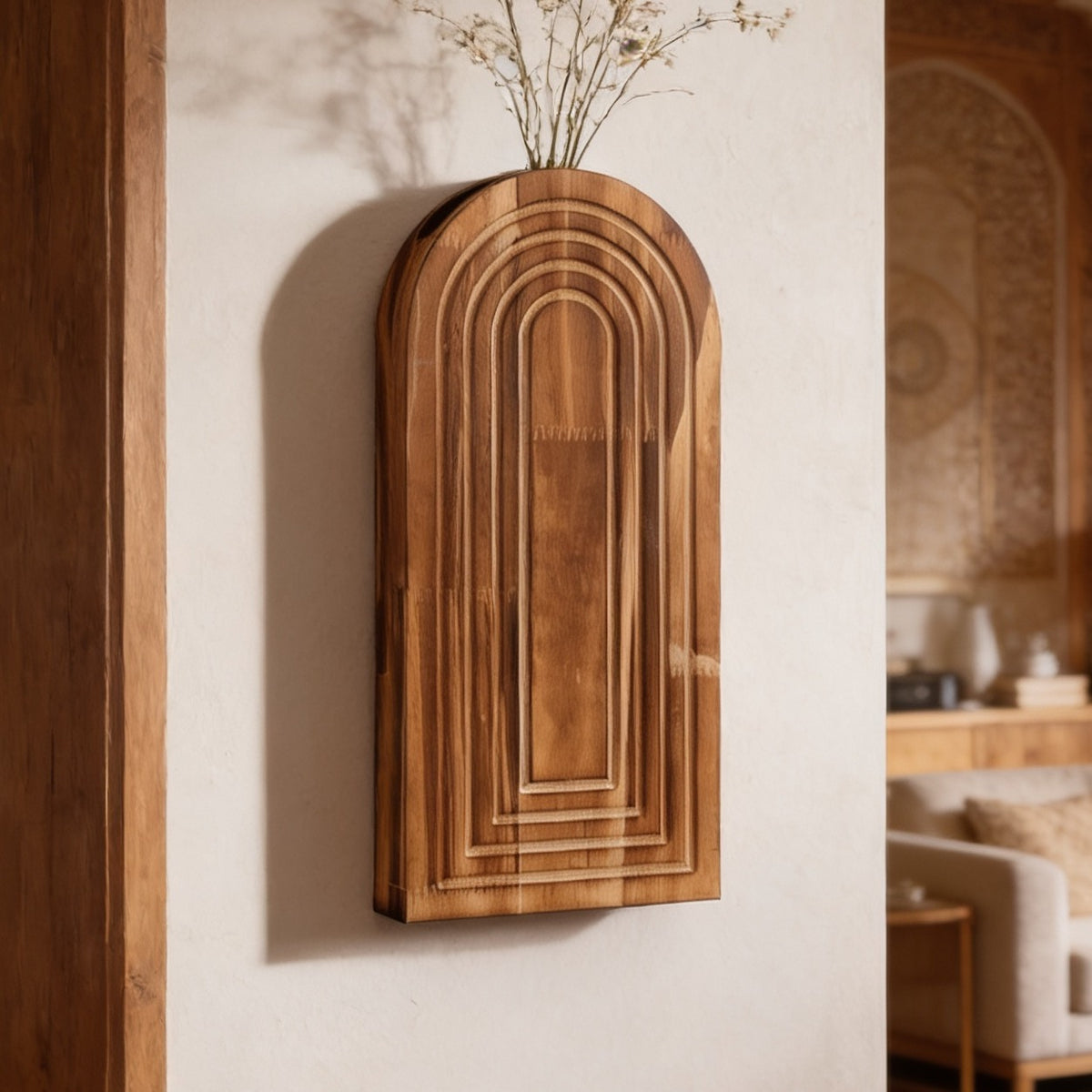 Carved arch wall vase with fine dried stems mounted beside an open doorway