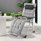 Light gray cushioned recliner on a patio next to a round white table and planters
