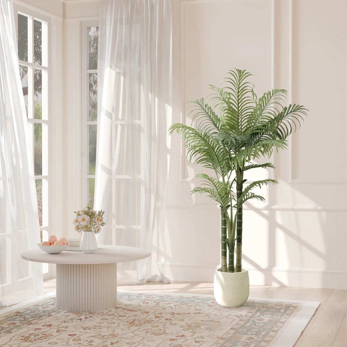 Areca palm by sheer curtains next to a round white coffee table on a rug