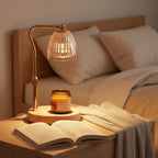 Warmer lamp on a bed beside an open book and a small amber jar candle