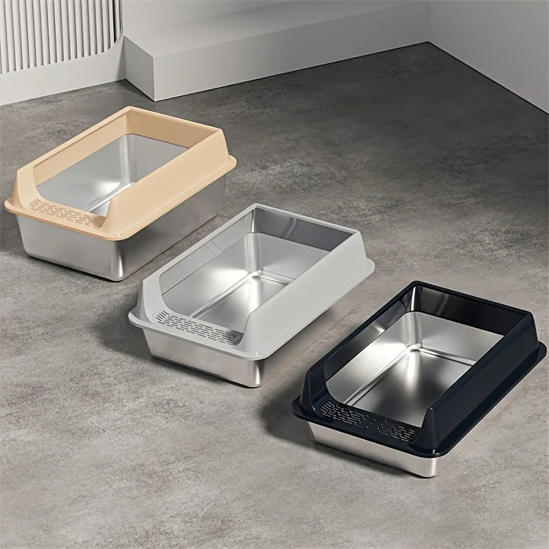 Three litter boxes lined up in beige, silver and black on a gray floor