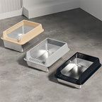Three litter boxes lined up in beige, silver and black on a gray floor
