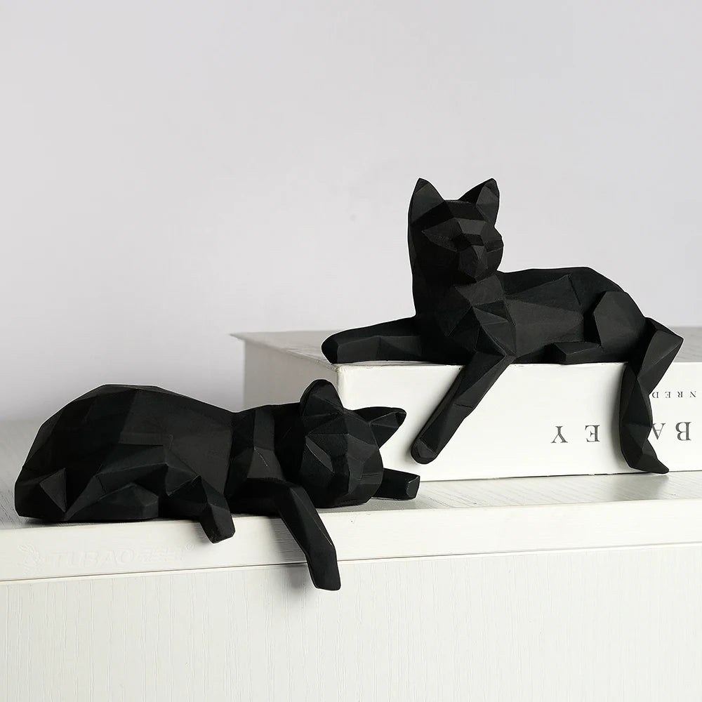 Black geometric cats, one seated on a book and one lying on a white ledge