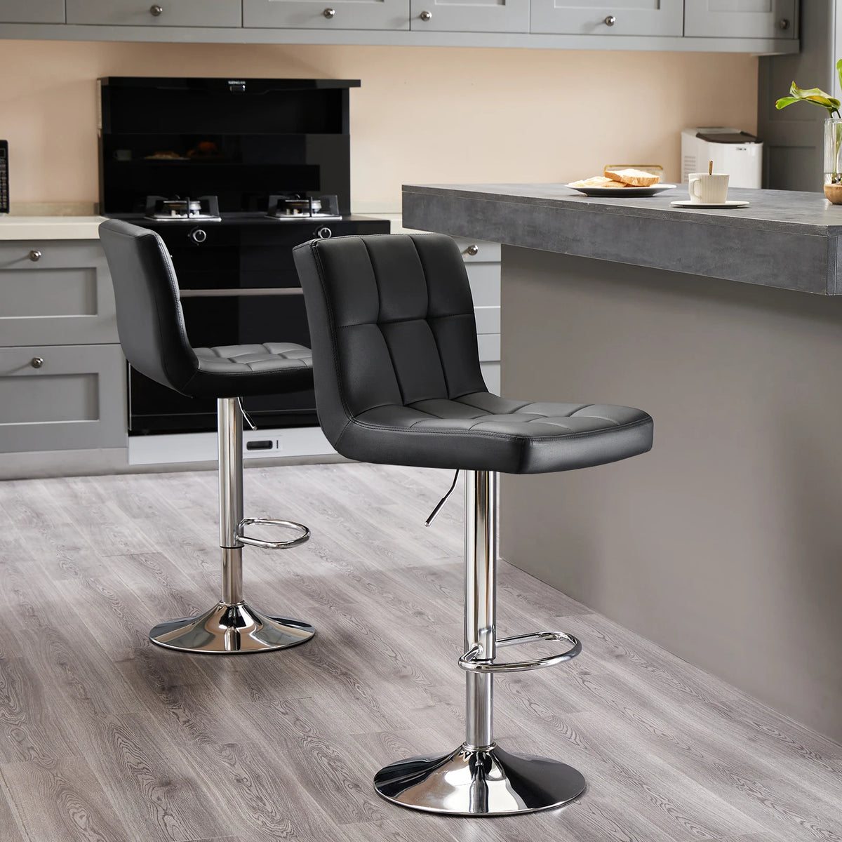 Two black stools along a gray countertop beside a stove in an open kitchen