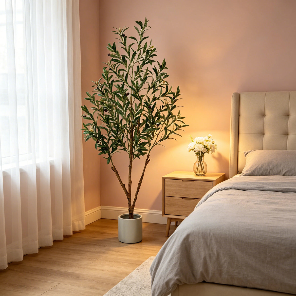 Faux olive tree in a bedroom corner beside a nightstand and a warm lamp