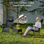 Two folding recliners set up on grass under a tree, one with a woman seated and reading