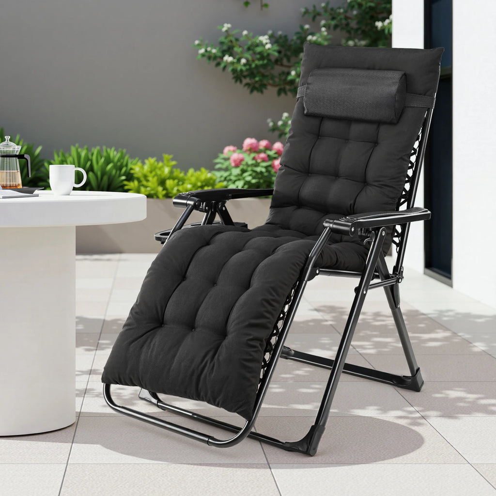 Dark gray padded recliner beside a white side table holding a coffee cup and flowers