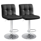 Close front view of two black tufted swivel stools standing together on white