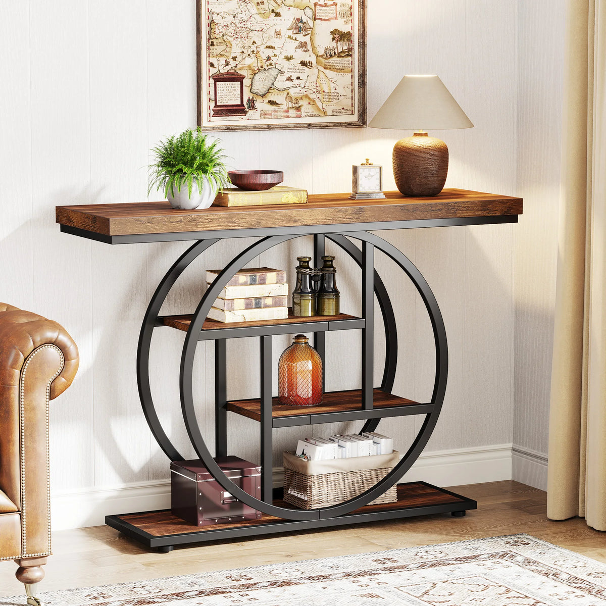 Console styled with bottles and books beside a brown leather sofa under framed art