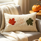 Cream lumbar pillow embroidered with red, tan and green maple leaves