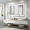 Backlit mirror reflecting daylight above a long white vanity with folded towels below