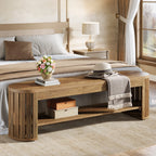 Wood bench at the foot of a bed with a box on its lower shelf and flowers on top