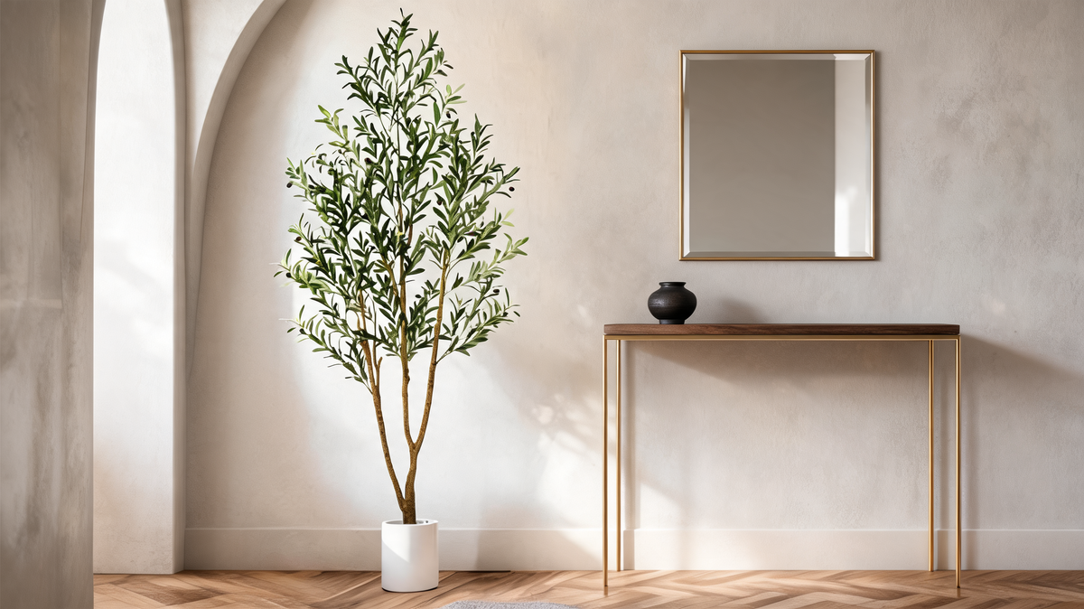 Faux olive tree in its white cylinder planter standing beside a hallway console