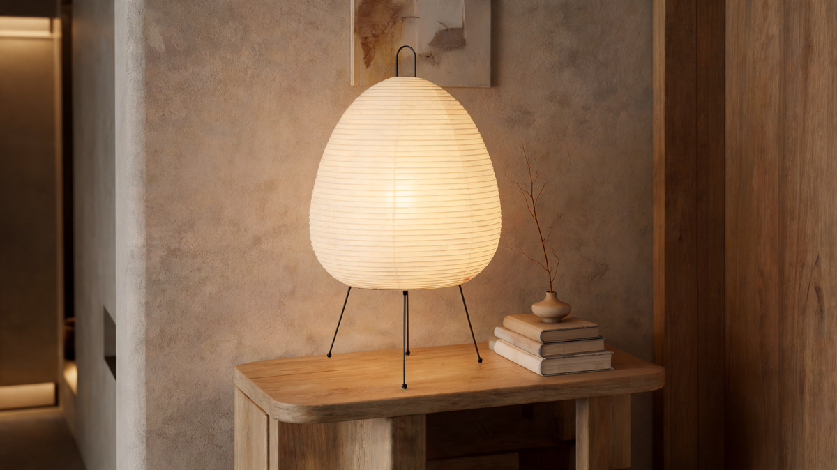 Wabi sabi paper shade lamp lit on three splayed wire legs on a wooden console