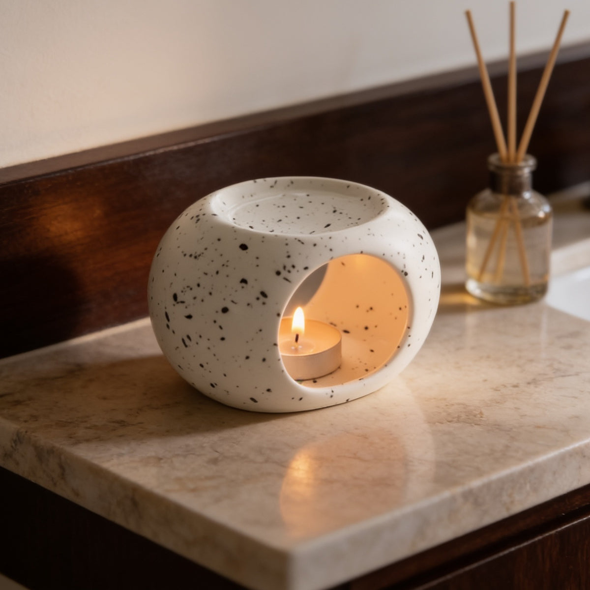 Speckled ivory warmer lit on a pale marble countertop in a bathroom
