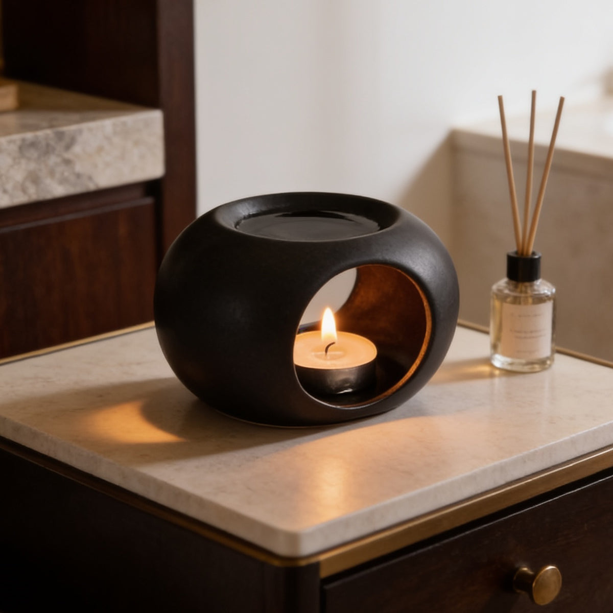 Black wax warmer glowing on a stone vanity top with a diffuser bottle to one side