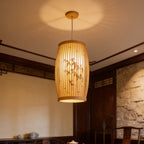Slim bamboo cylinder shade lit just below a white coffered ceiling in a quiet room