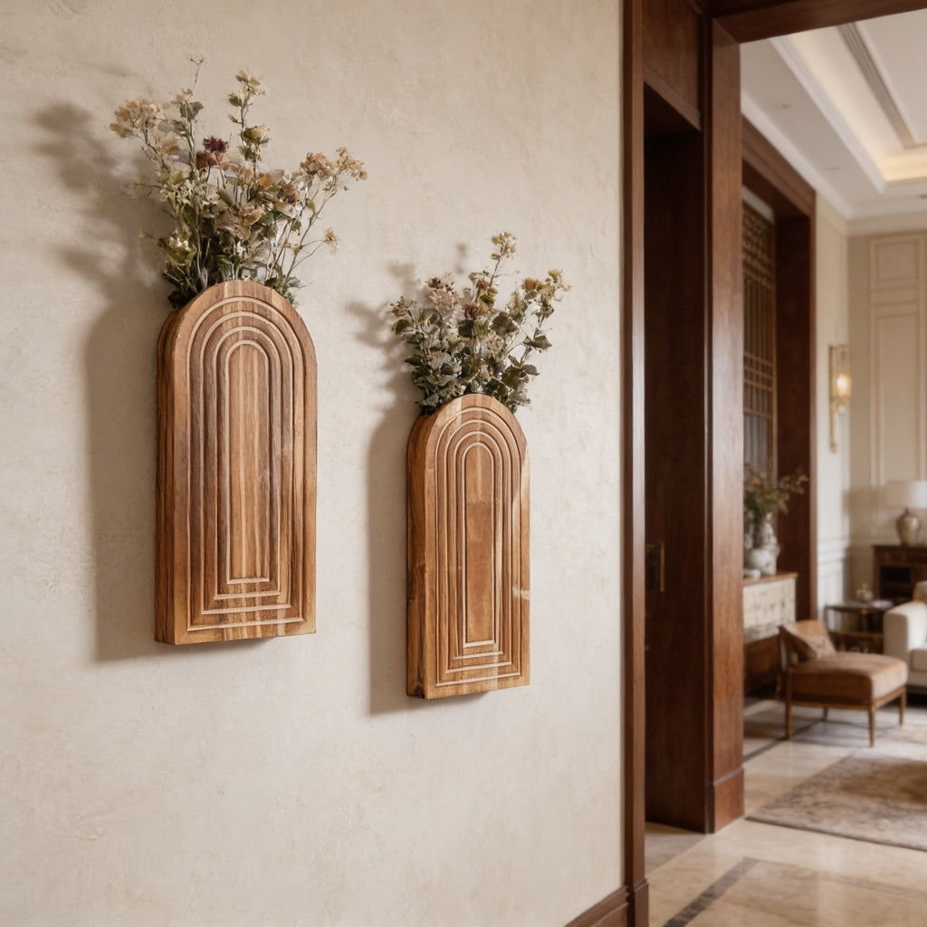 Arched wall vases filled with pink and white dried blooms near a wide doorway