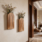 Arched wall vases filled with pink and white dried blooms near a wide doorway