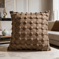 Braided brown leather cushion standing upright on a console beside stacked books