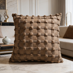 Braided brown leather cushion standing upright on a console beside stacked books