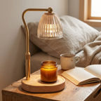 Candle warmer lamp glowing over an amber jar candle beside an open book