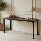 Wide double desk holding stacked books and a table lamp seen straight on