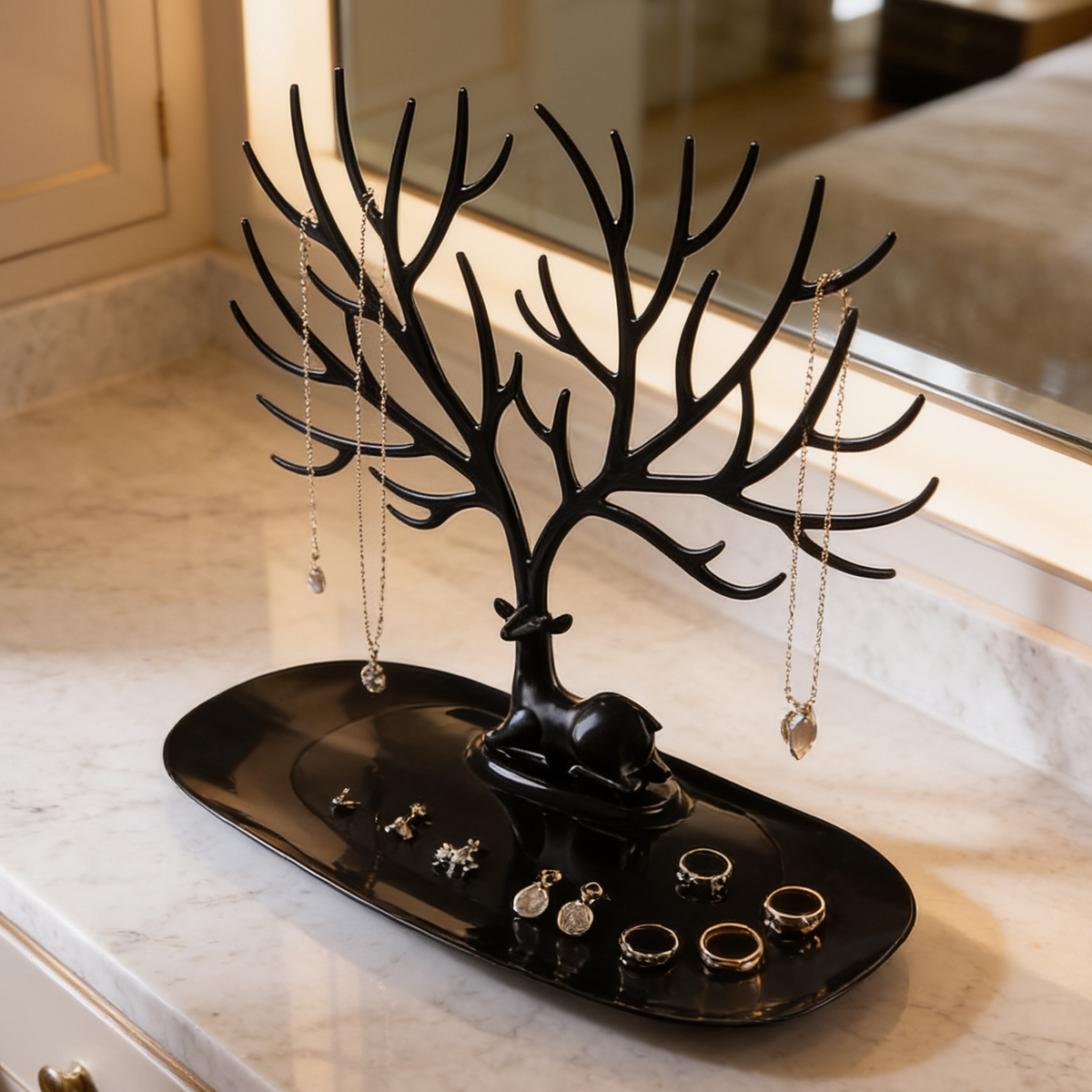 Black branching jewelry stand on an oval tray holding rings and necklaces