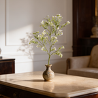 Sunlit white blossom stems in a small vase casting a soft shadow on the wall