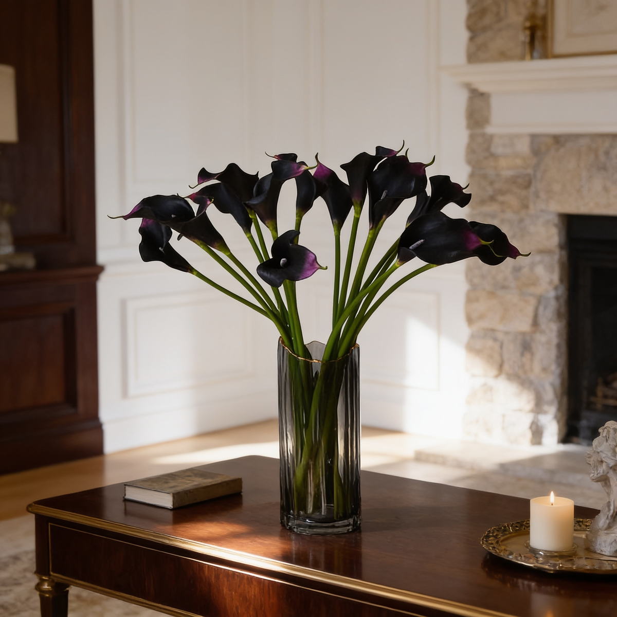 Deep plum calla lilies in a clear glass vase against a paneled white wall