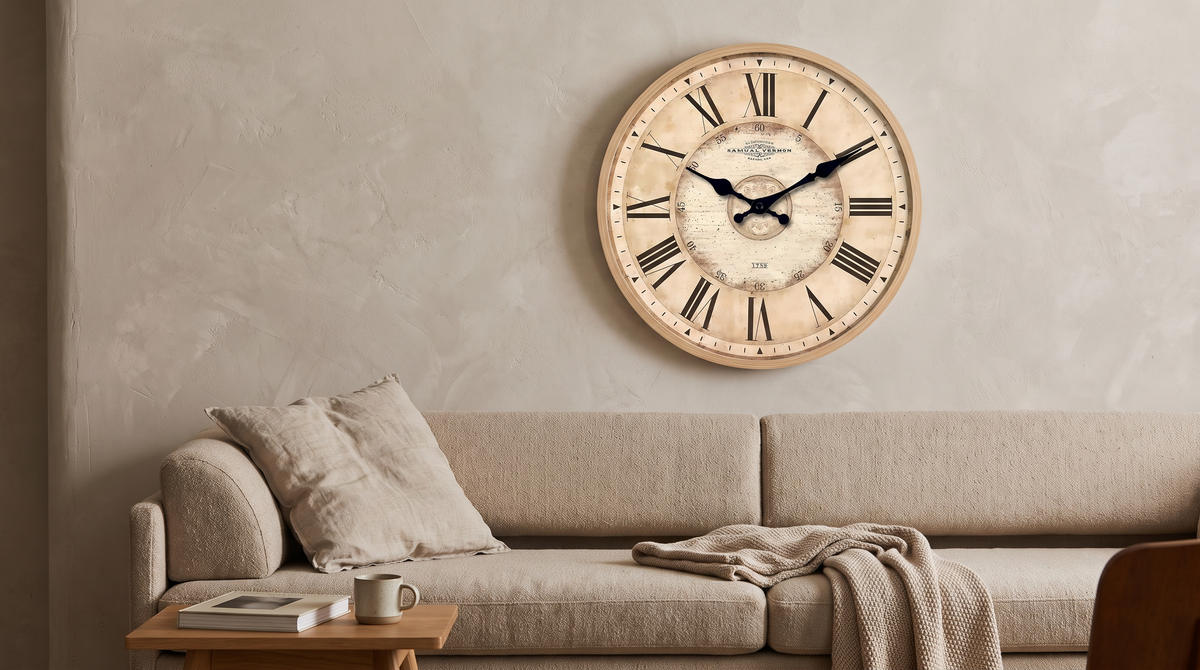 Vintage Roman numeral wall clock hung above a sofa in a neutral living room