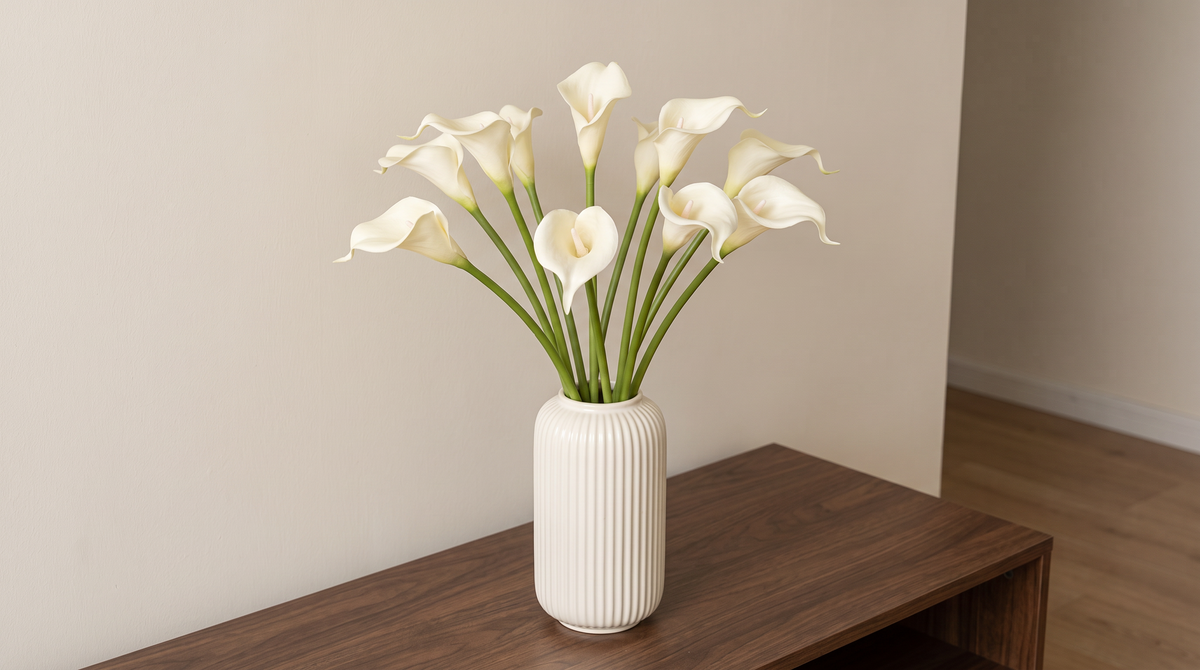 White faux calla lilies in a ribbed ceramic vase on an entryway console