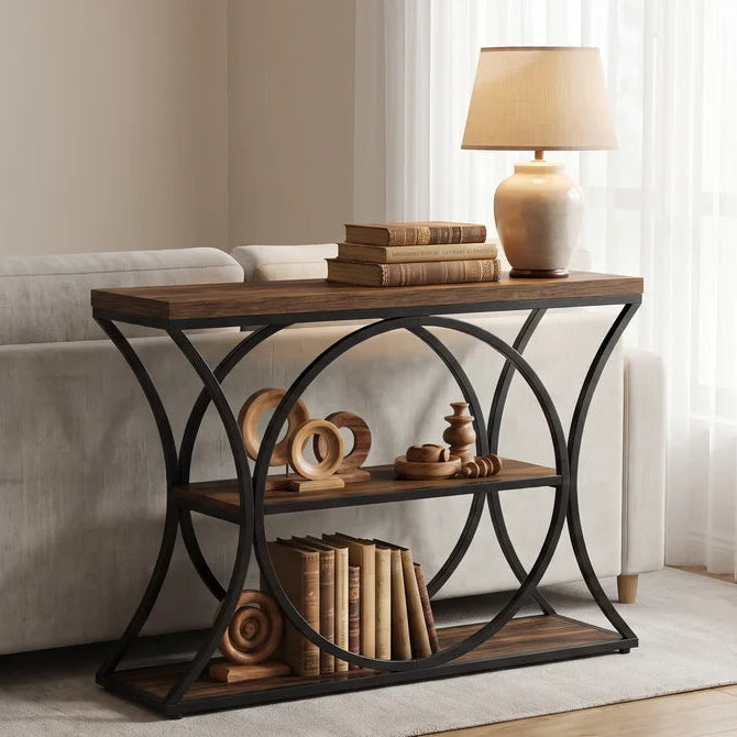 Console behind a sofa holding a lit lamp, books and a woven basket