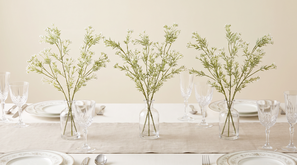 Faux gypsophila in bud vases along a dressed dining table