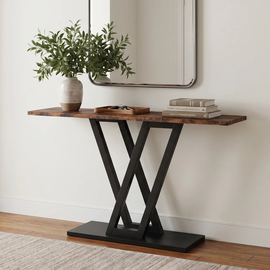 Wood top console table on a black V shaped steel base under a hallway mirror