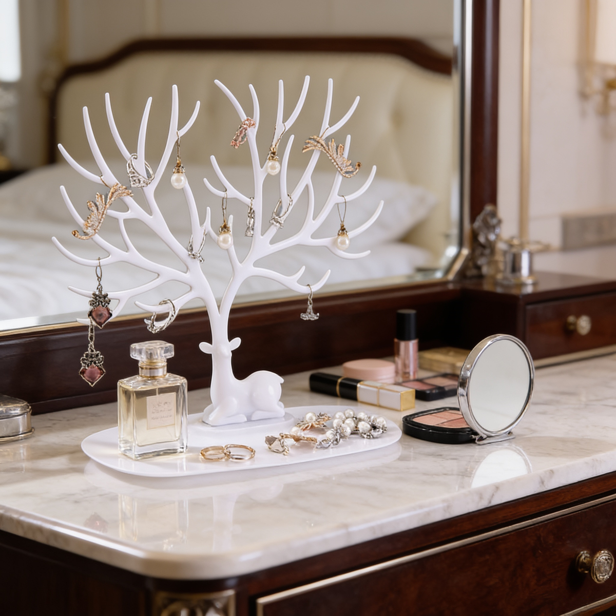White jewelry tree on a dark wood dresser among cosmetics and a round mirror