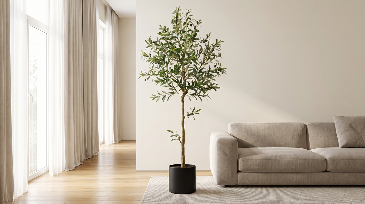 Faux olive tree in a black pot beside a sofa in a living room