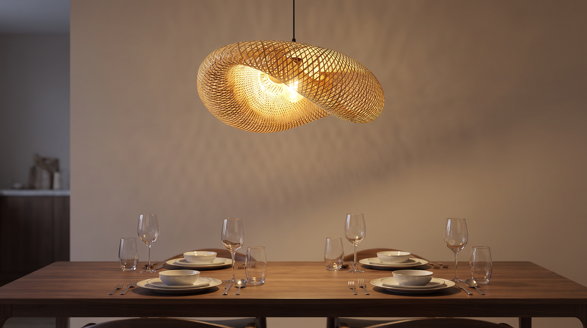 Hand woven bamboo pendant light lit above a dining table