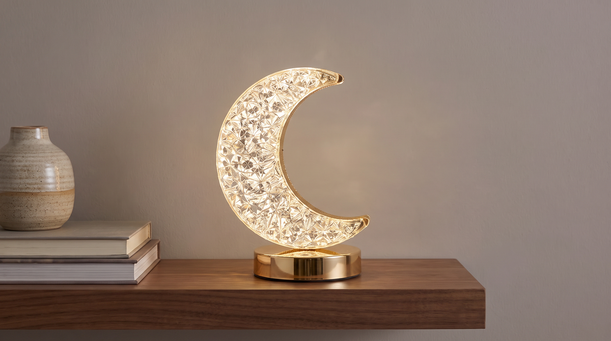 Crescent moon night light on a walnut shelf beside books