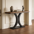 Narrow console with an hourglass black base and wood top styled with a vase and books