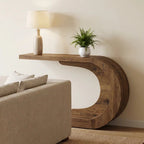 Sculptural wood console beside a cream sofa with a lamp and a small plant