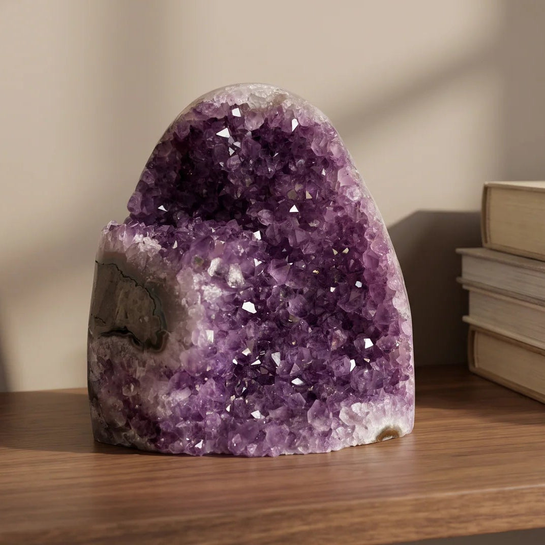 Close view of the amethyst geode on a wood table with stacked books behind