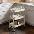 Cream three tier rolling cart in a kitchen corner holding glass jars and bottles
