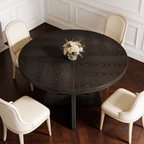 Black round dining table with cream chairs and a small vase of flowers